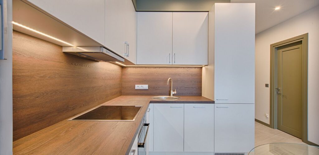 Wood-effect splashback and under-cabinet lighting in a fitted kitchen